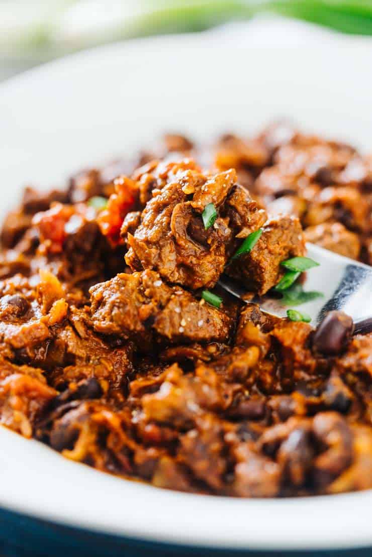 slow cooked chili in a white bowl with a fork