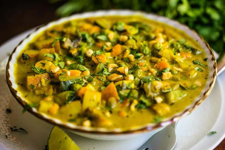 A bowl of veggie curry with coconut milk sprinkled with cashews and cilantro.