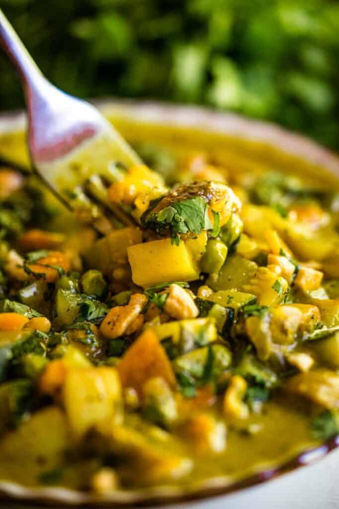 A close up of a bowl of curry with a fork in it. 