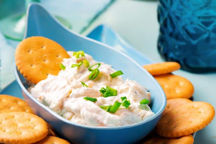 Caramelized onion dip in blue dish with crackers