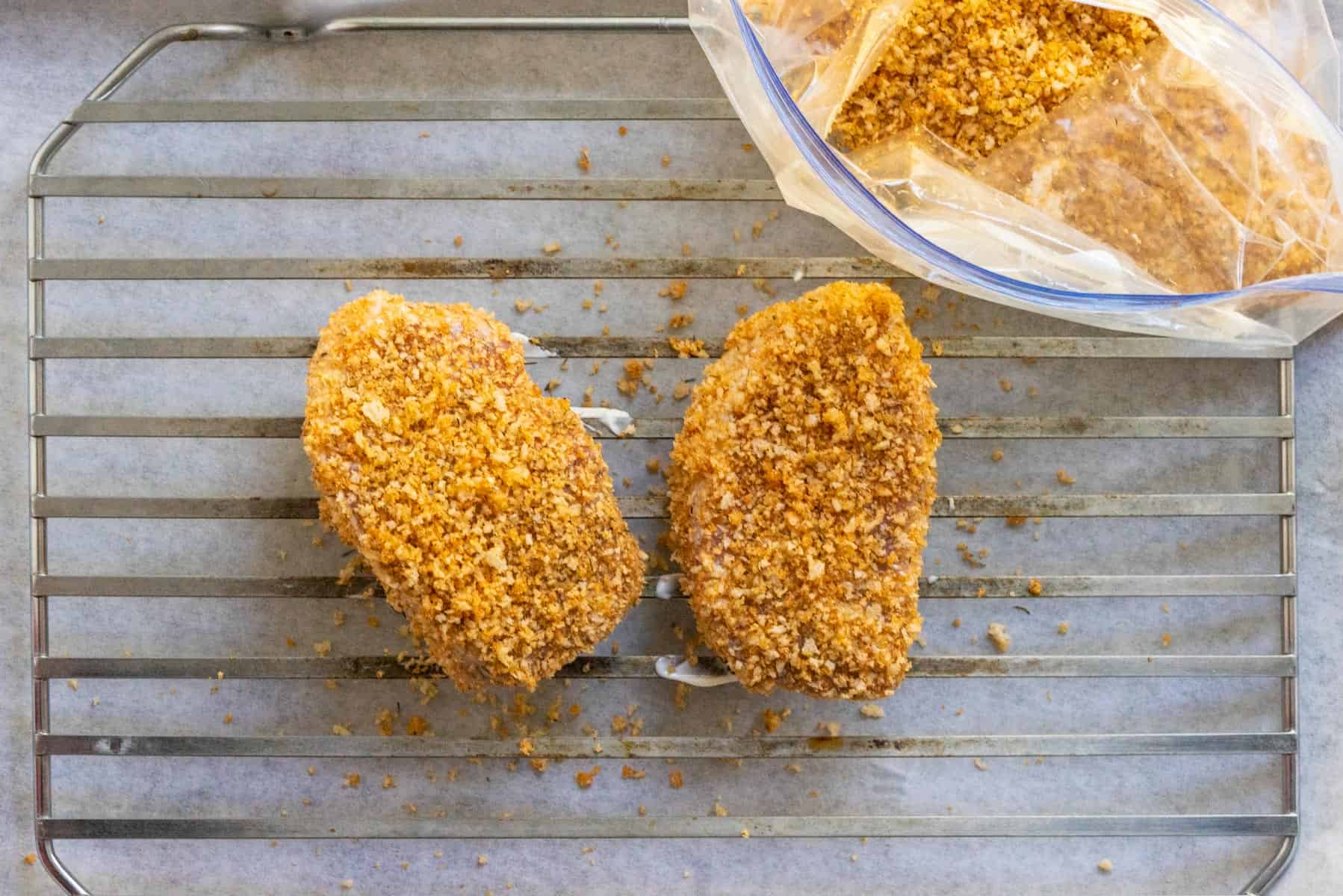 2 pork chops covered in bread crumbs on a rack