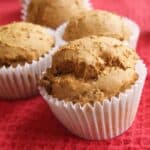 pumpkin muffins in white wrappers on a red cloth