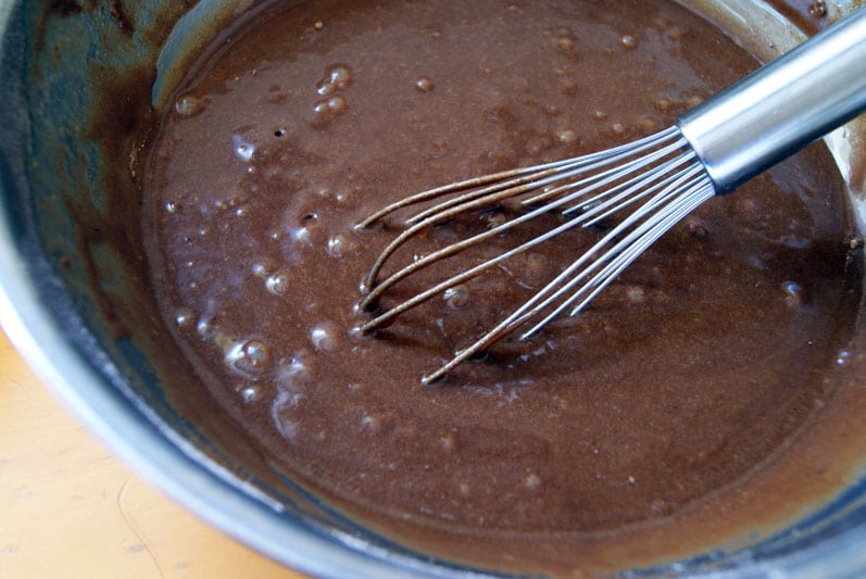 Brownie batter in a silver bowl and whisk