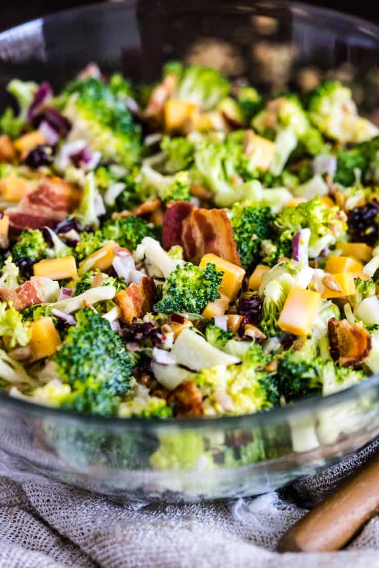 Glass bowl full of sweet broccoli salad with bacon, currants, onion, cheese and sunflower seeds