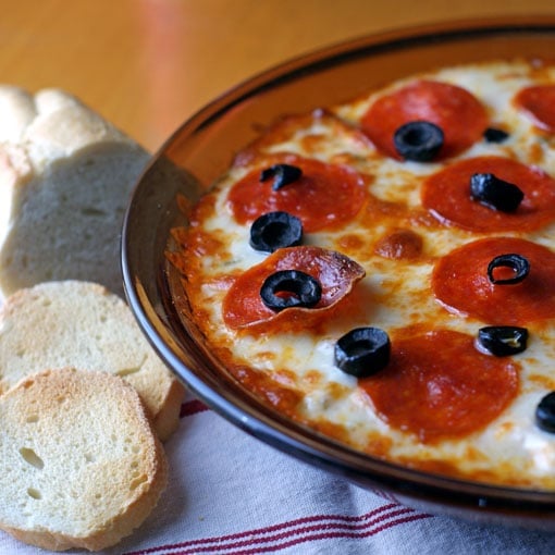 Baked Pizza Dip in pie dish with a white and red towel and toasted bread slices
