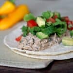 2 corn tortillas with chicken, lettuce, tomato and avocado on a tabletop