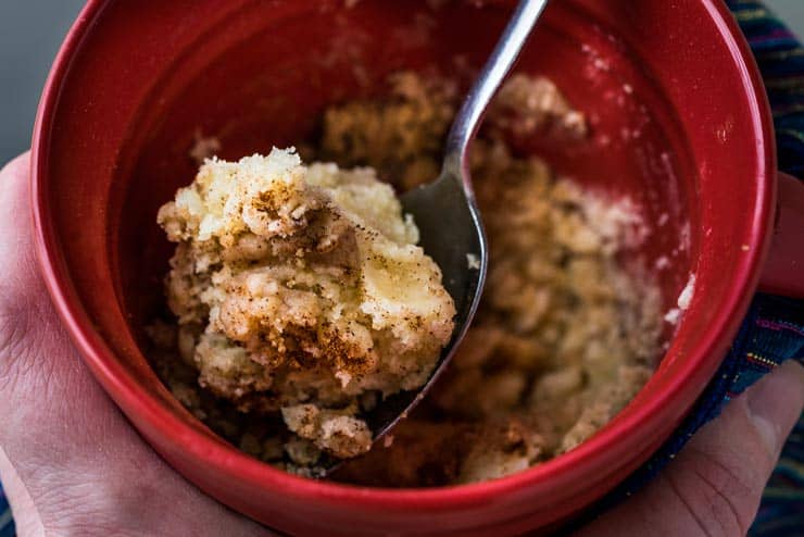 Up close of coffee cake in a mug and a spoon inside. 