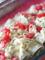 unbaked green chile cheese enchiladas in glass dish