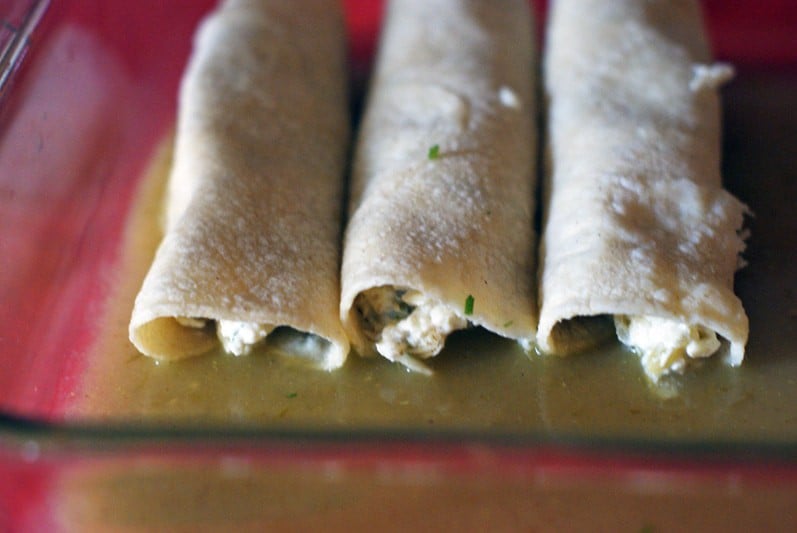 3 corn tortillas filled with cheese mixture in green enchilada sauce