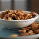 honey almonds in a white bowl on blue plate