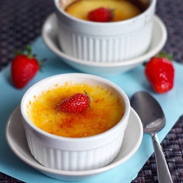 Two Creme Brulee in white dishes with strawberries