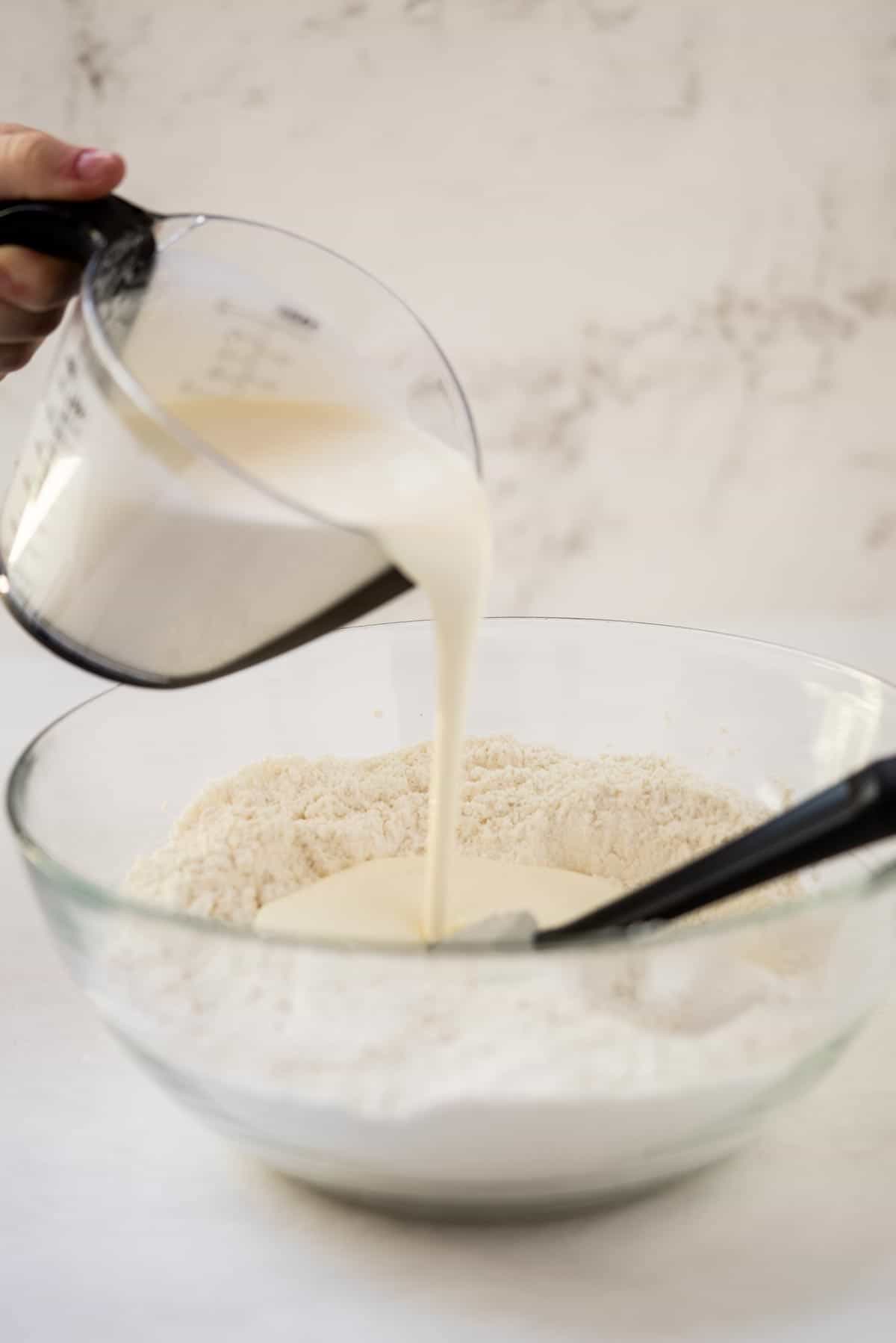 Whipping cream being poured into a bowl with other ingredients