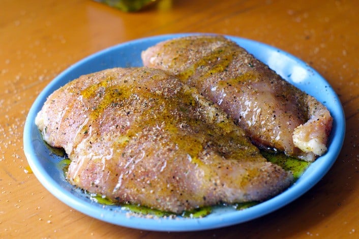 two seasoned chicken breasts on a blue plate