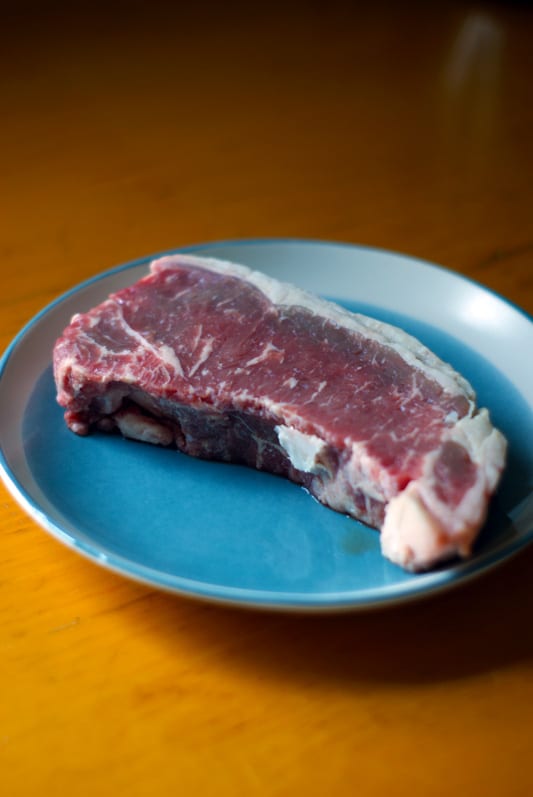 raw new york steak on a blue plate