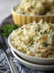 Cabbage coleslaw in white bowl on grey napkin and fork