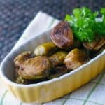 roasted brussels sprouts in a yellow dish with parsley