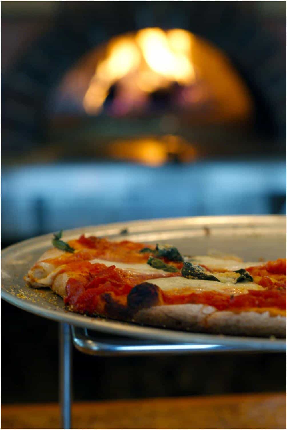 pizza on a rack with a fire behind