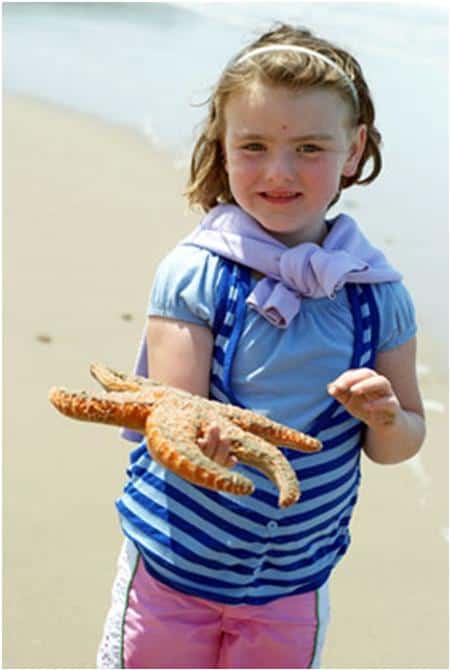 young girl holding a starfish on the beach