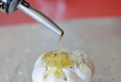 A head of garlic with olive oil and salt and pepper getting ready to be roasted