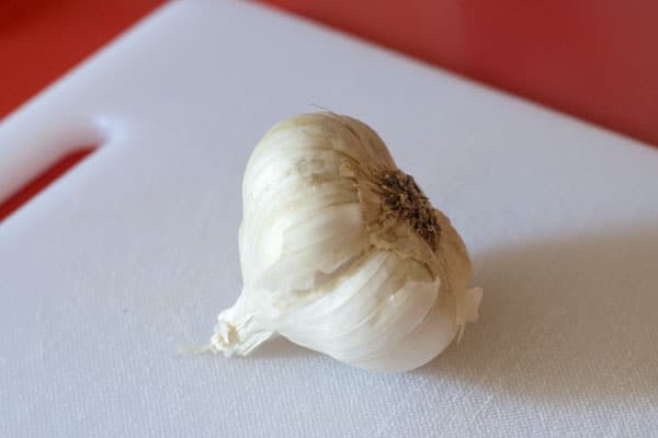 A head of raw garlic on a white cutting board