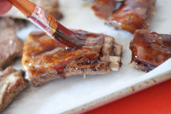 brushing the sauce over the ribs on a baking sheet