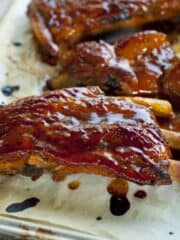 sticky ribs on a baking sheet with sauce on them