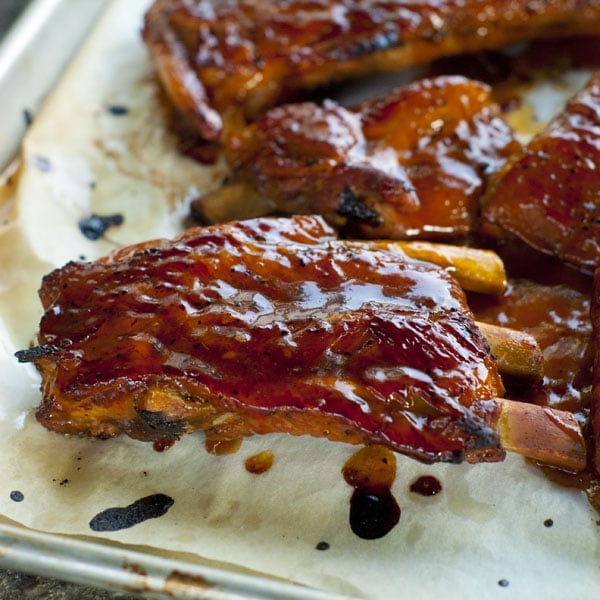 sticky ribs on a baking sheet with sauce on them 