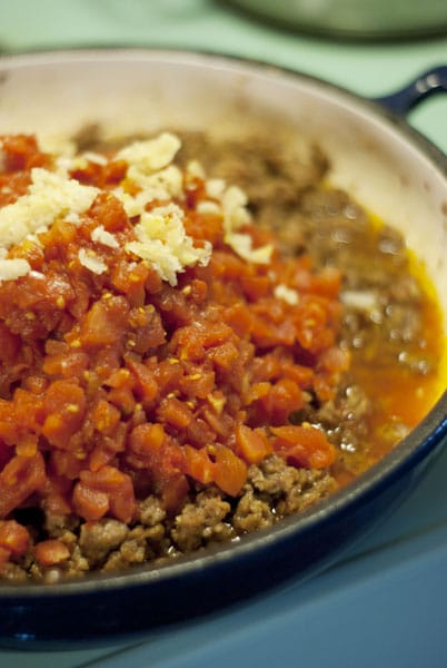 tomatoes, sausage, and garlic in a pan on the stove