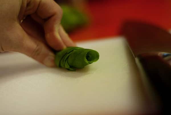 rolled basil leaves on a cutting board