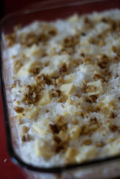 chopped walnuts on top of the butter and cake mix in a glass baking dish