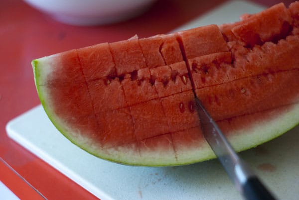 Making vertical lines on a watermelon with a knife.