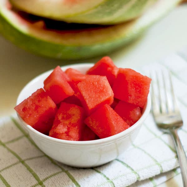 Diced watermelon in a white bowl on a towel