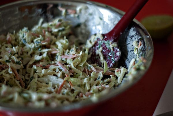 tangy slaw in a metal bowl and red spatula