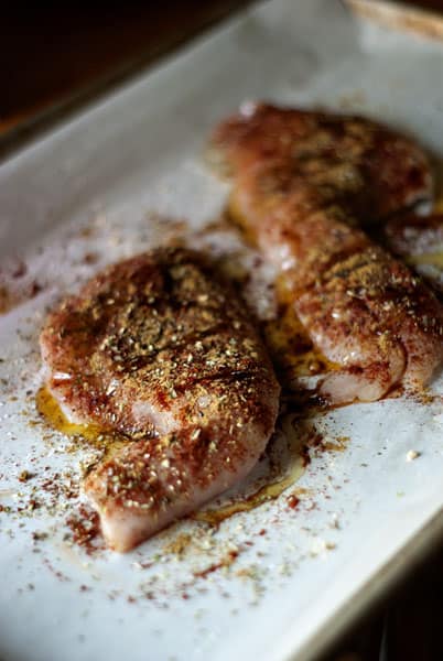 seasoned raw white fish on a baking sheet