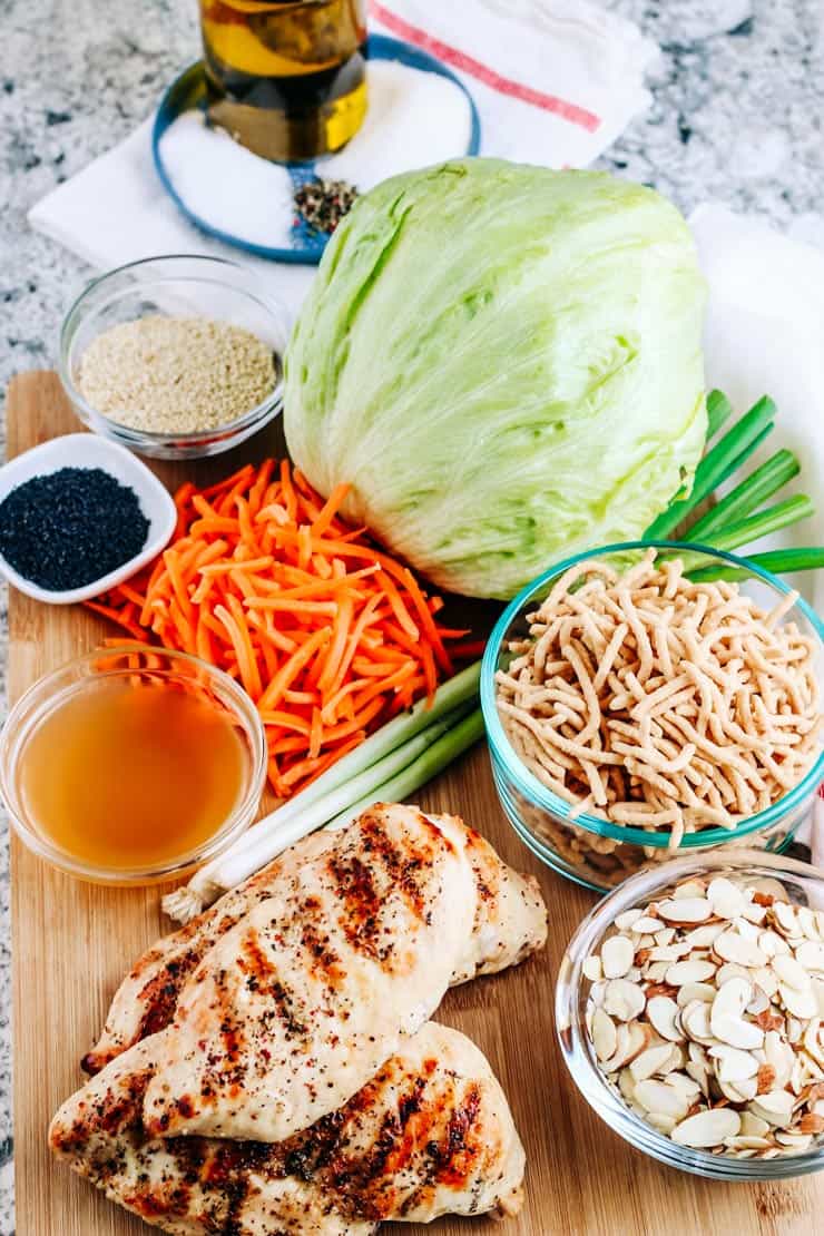 Grilled chicken, cabbage, carrots, noodles, almonds and poppy seeds on cutting board