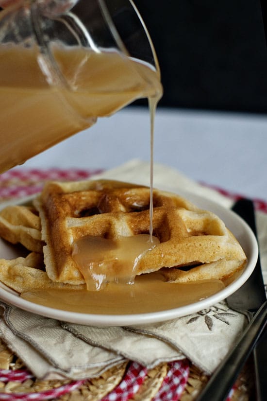 Buttermilk syrup being poured on a stack of waffles