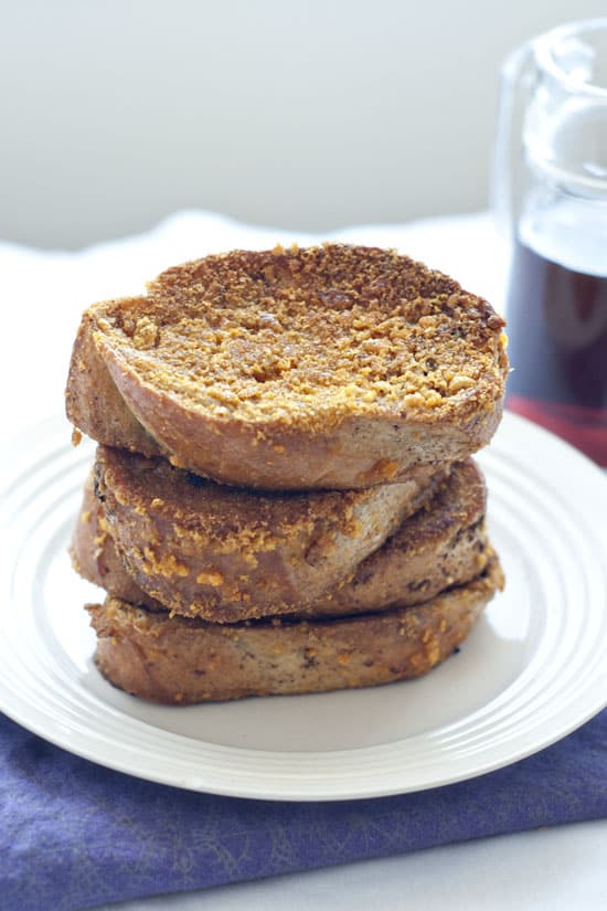 Delicious french toast stacked on a white plate on a table.