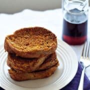 Easy french toast on a white plate next to a glass of maple syrup.