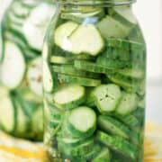 Delicious Refrigerator Pickles in two large glass mason jars on a wooden table.