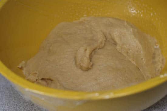 Easy German Crumb Cake dough in a greased yellow bowl covered with plastic wrap.