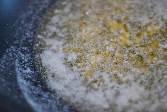 Cooking butter and garlic in a large black skillet.