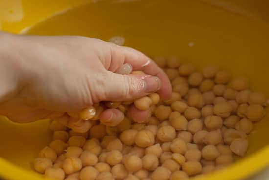 Chickpeas submerged in water in a large yellow bowl.