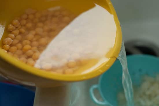 Pouring excess water out of Yellow bowl full of chickpeas .