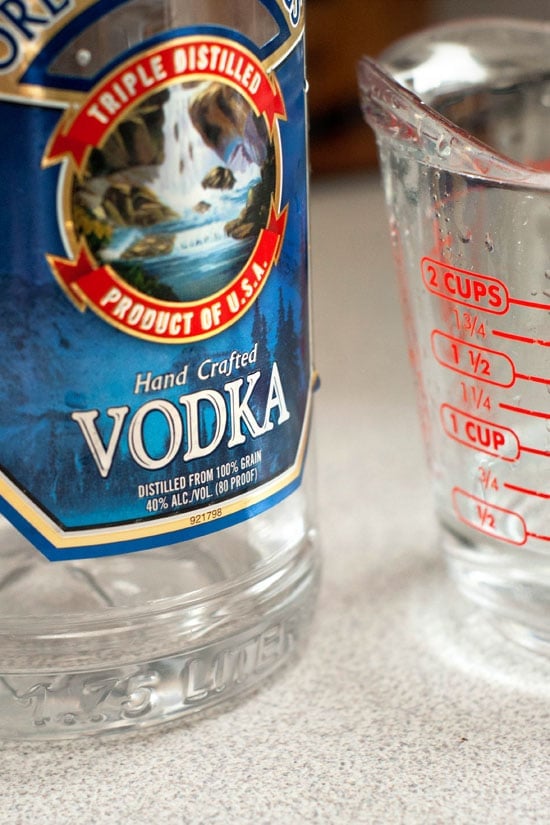 Hand Crafted Vodka next to a glass measuring cup on a table.