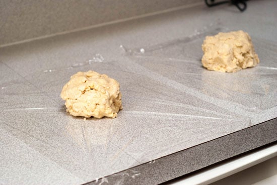 Two separate pie crust balls in clear plastic wrap.