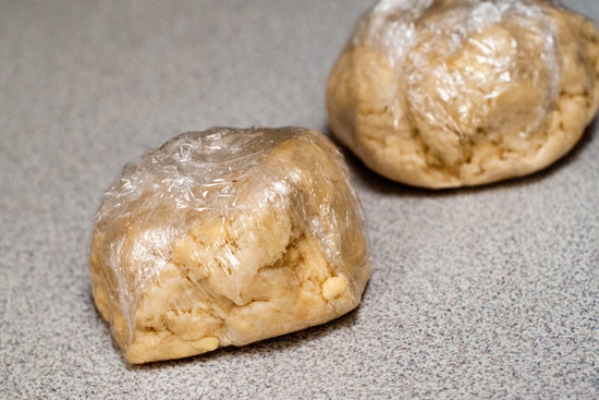 Easy pie crust dough rolled into balls in plastic wrap.