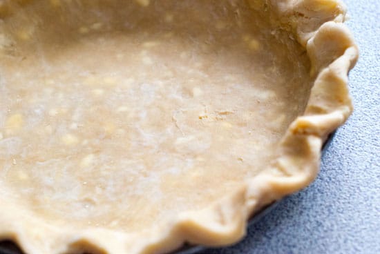 Buttered pie crust dough in a pie dish on a table.