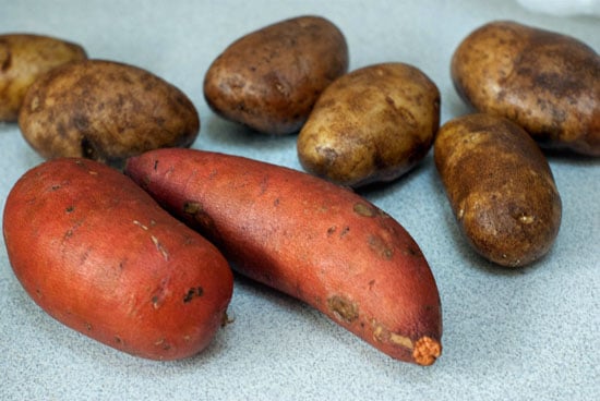 russet potatoes and sweet potatoes on a table.