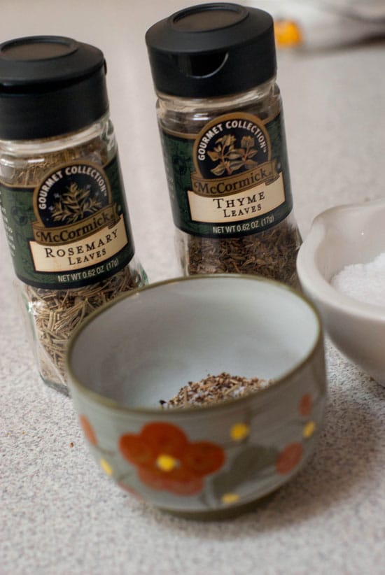 Rosemary leaves and thyme leaves mixture in a small bowl.