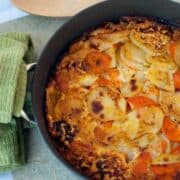 Easy Sweet Potato Gratin recipe in a large black skillet next to a wooden spoon.